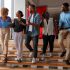 A diverse team of young creative professionals talking and laughing while walking down a modern office staircase.